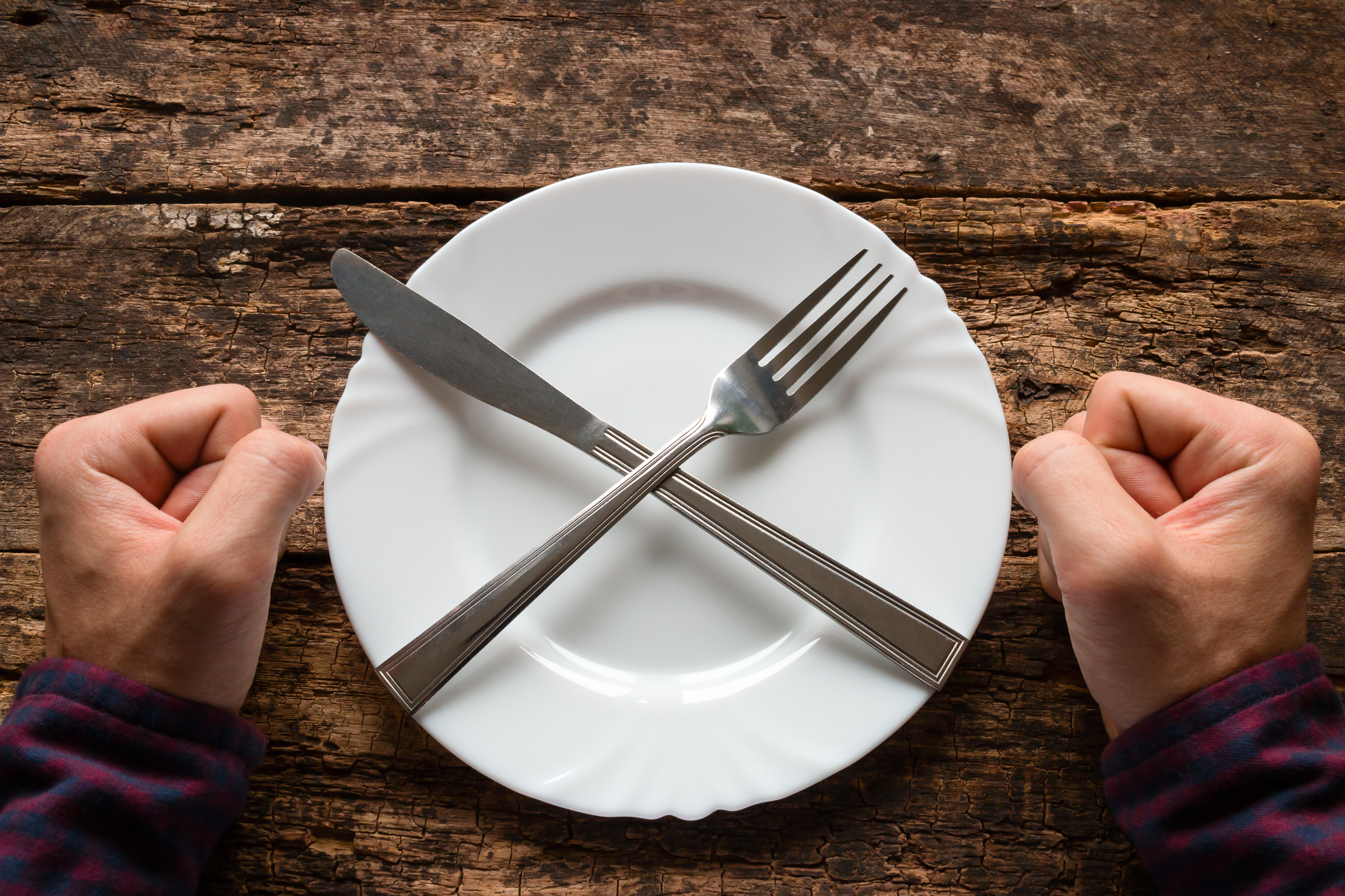 man refuses to eat spoon and fork on a plate stacked in the shape of a cross